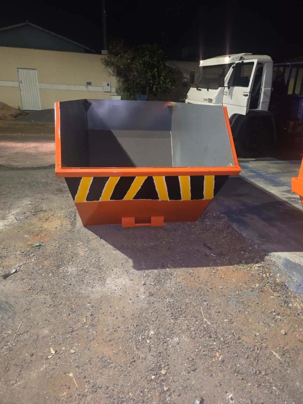 Caçamba nova pintada com faixas de segurança preto e amarelo